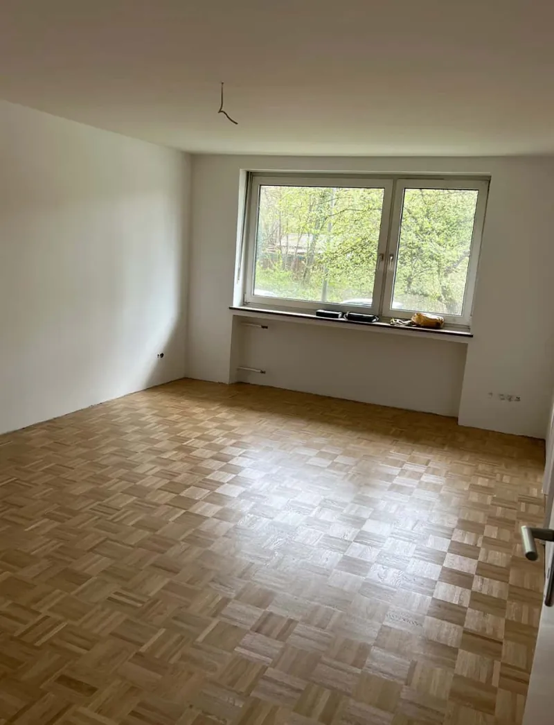 Leerer Wohnraum mit vorhandenem Parkettboden im Bestand