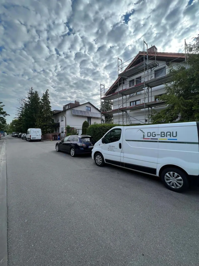 DG BAU Transporter vor einem eingerüsteten Wohnhaus